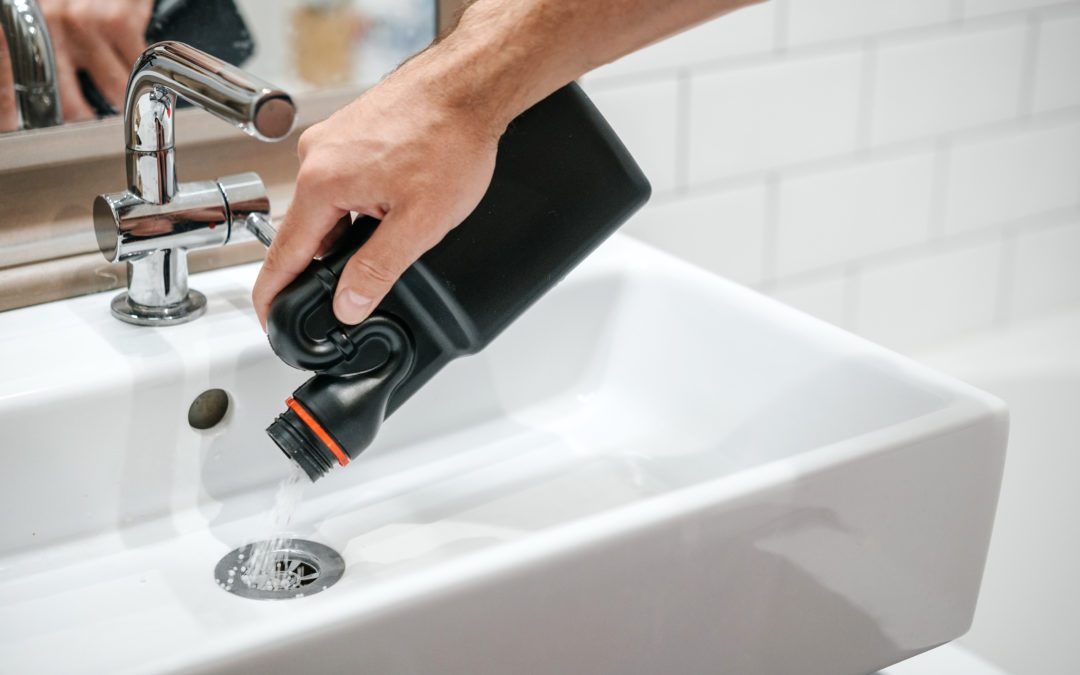 Homeowner pouring chemical drain cleaner down bathroom sink