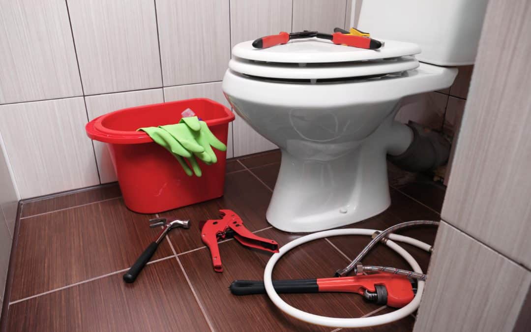 Plumber's tools on and around bathroom toilet