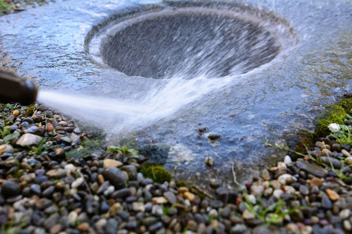 Highly-pressurized water being aimed at a drain.