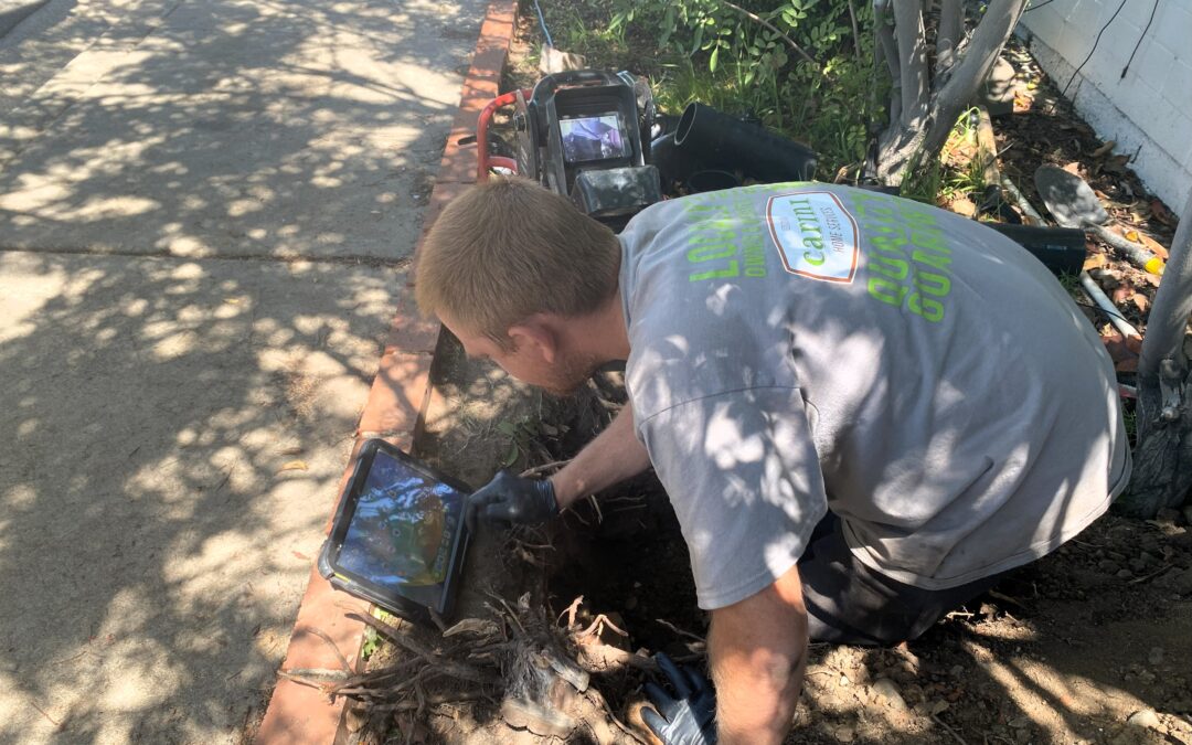 Plumber in a trench performing a sewer inspection using a ridgid sewer camera.