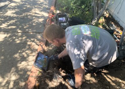 Plumber in a trench performing a sewer inspection using a ridgid sewer camera.